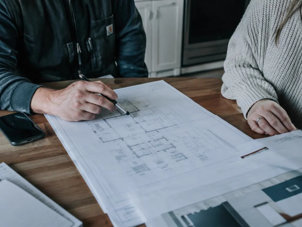 Tradesperson reviewing plans with a homeowner at a kitchen table